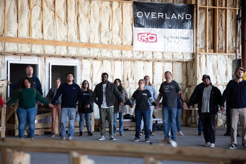 Church members clasp hands and pray during a beam signing event at Upperroom's new location...