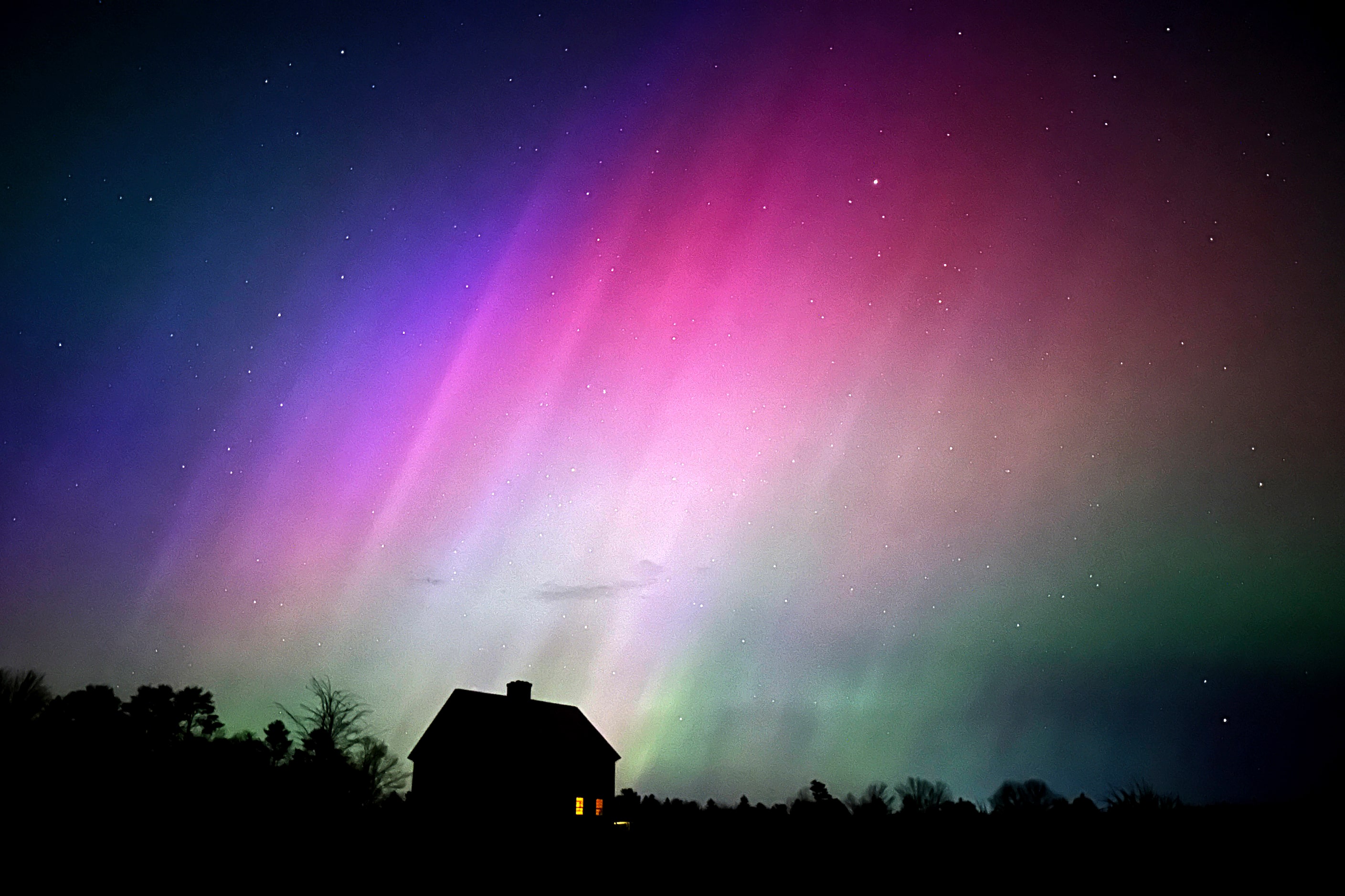 The northern lights flare in the sky over a farmhouse, late Friday, May 10, 2024, in...