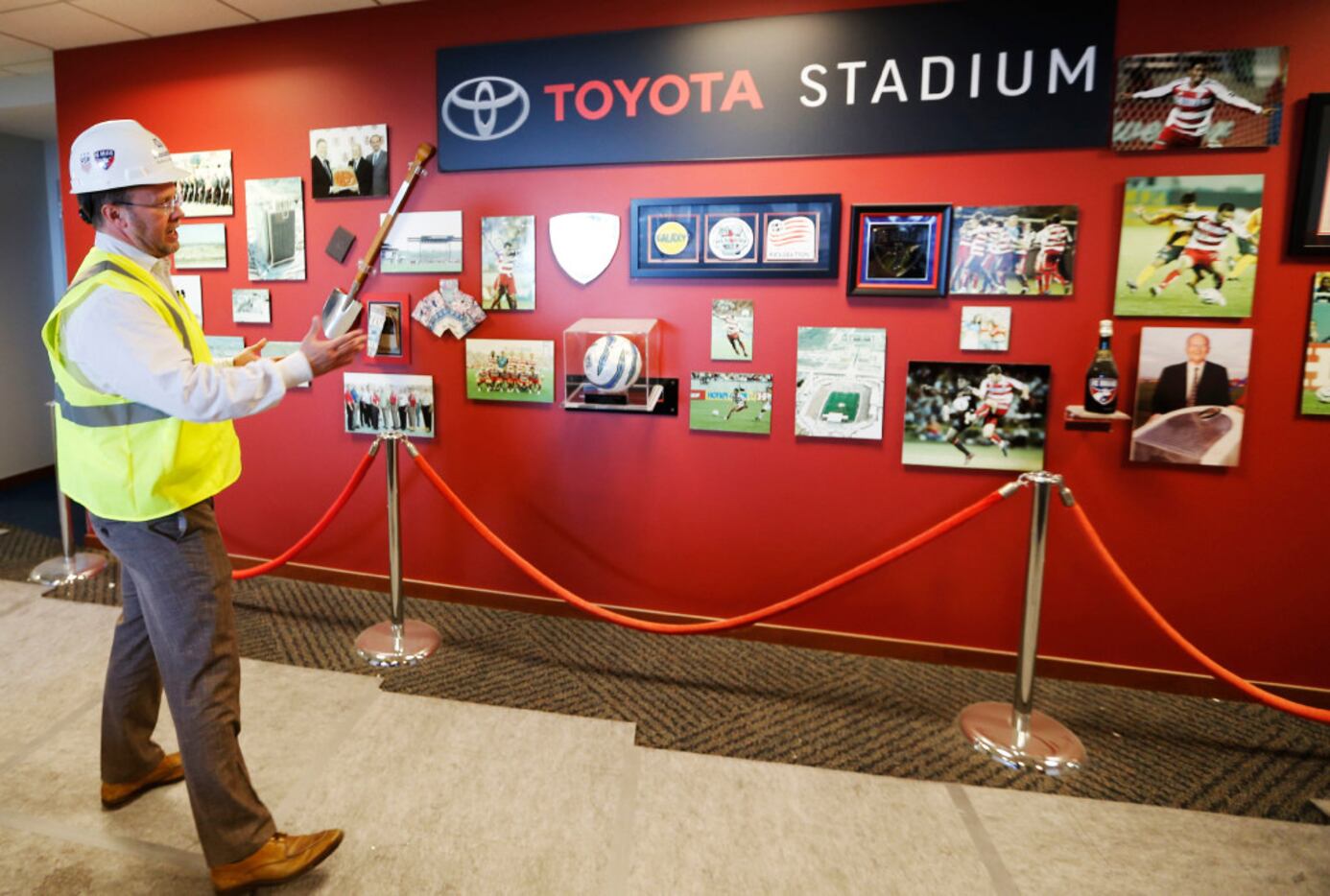 Hunt points out a few historical items on a wall outside the suites at Toyota Stadium. 