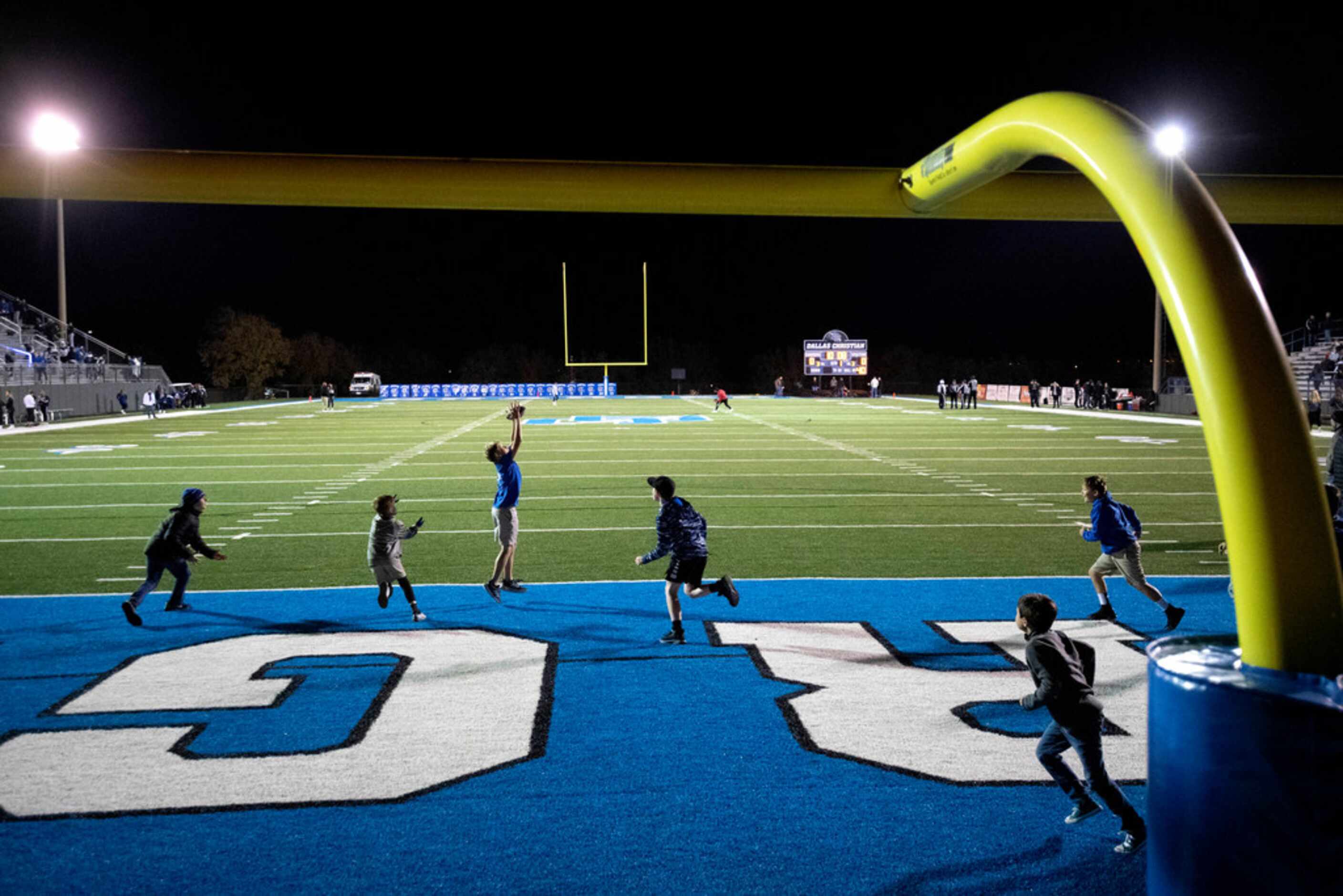 Boys play pick-up football on the field before the start of a high school football playoff...