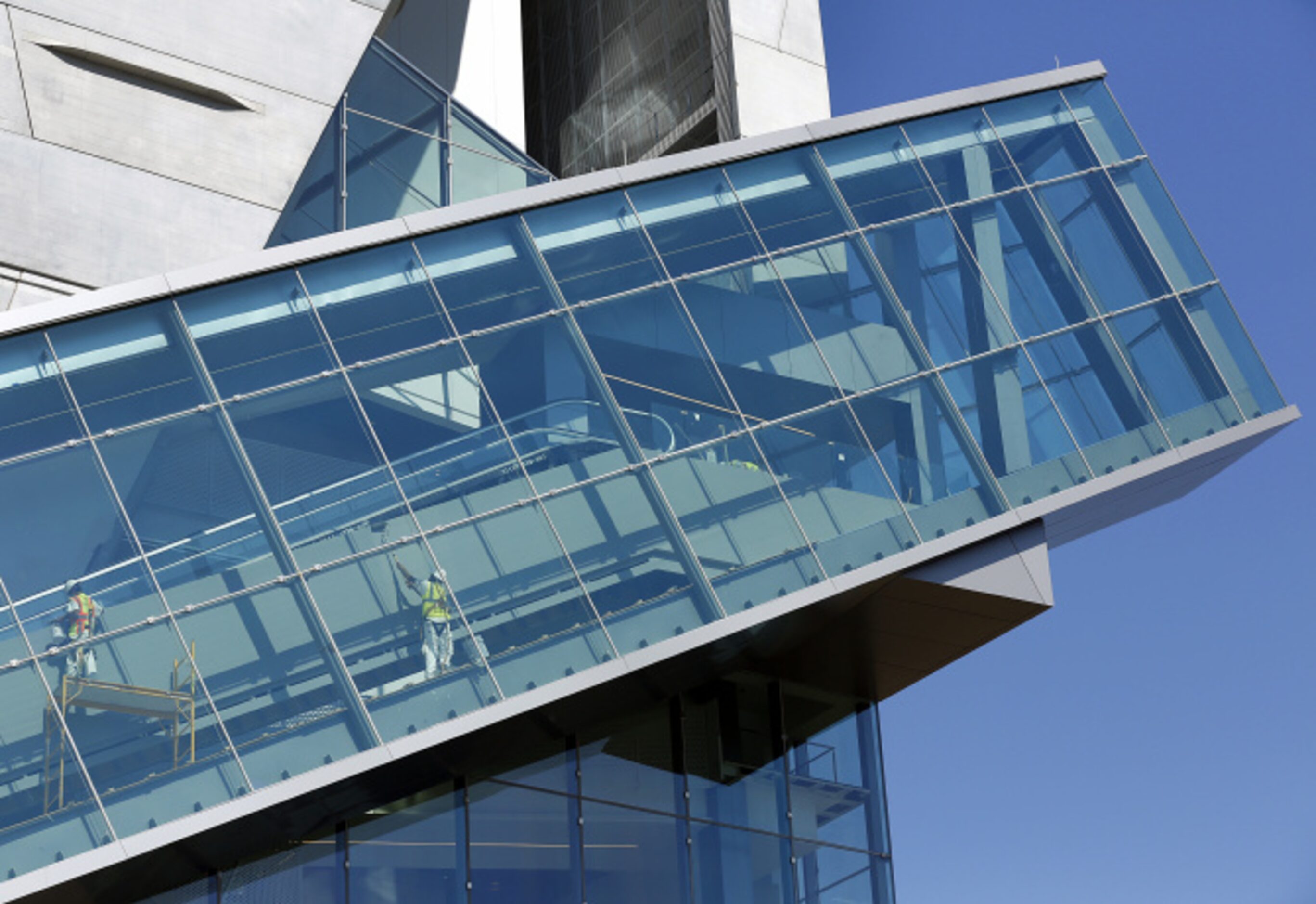 Workers paint the glass-enclosed escalator.