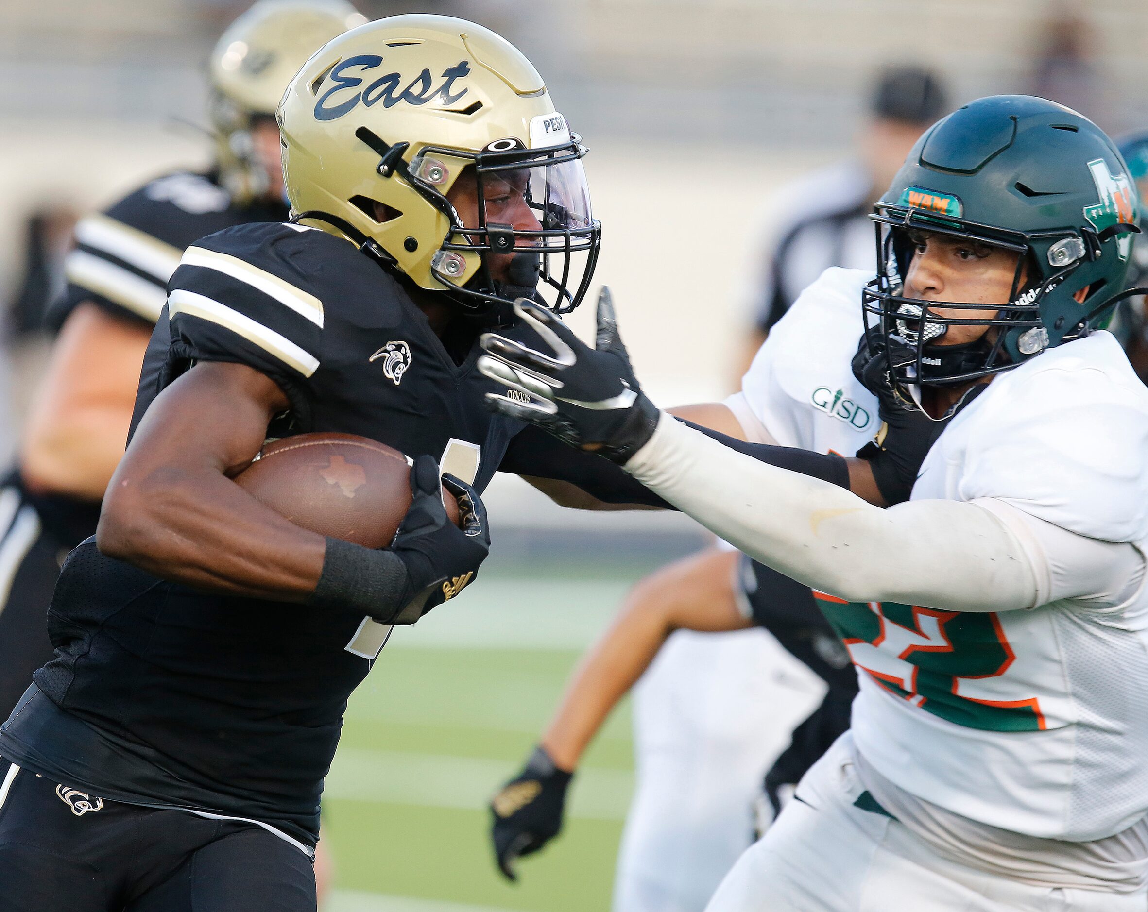 Plano East Senior High School running back Daniel Fayombo (4) tries to stiff arm through the...