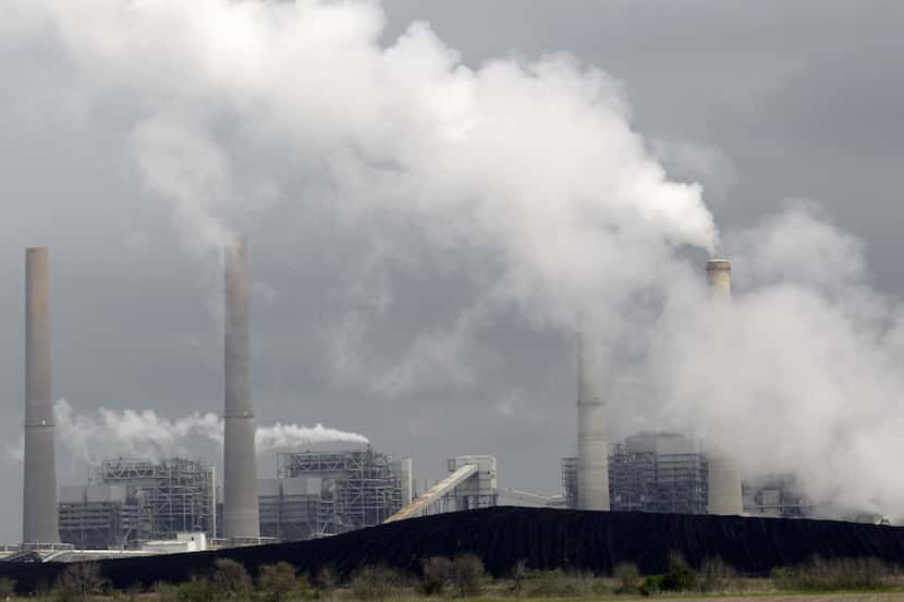 FILE - In this March 16, 2011, file photo, exhaust rises from smokestacks in front of piles...