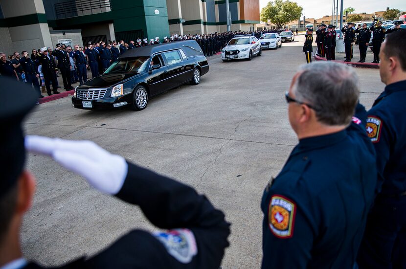  Officers salute as a hearse carrying the body of Euless police officer David Hofer passes...