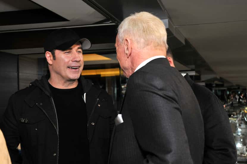John Travolta talks with Jerry Jones in the Jones suite at AT&T Stadium during Super Bowl...