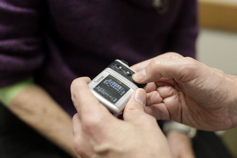 Endocrinologist Dr. Howard Baum checks the insulin pump of patient Connie Hedgecoke of...