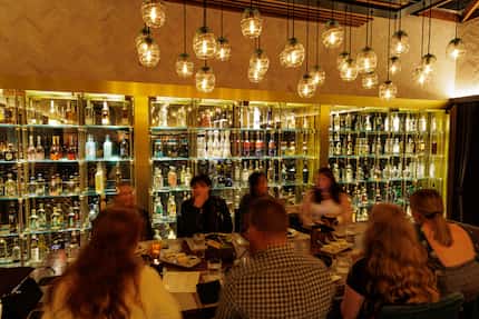 The liquor wall at The Mexican in Dallas shows off some of its bottles of tequila and...