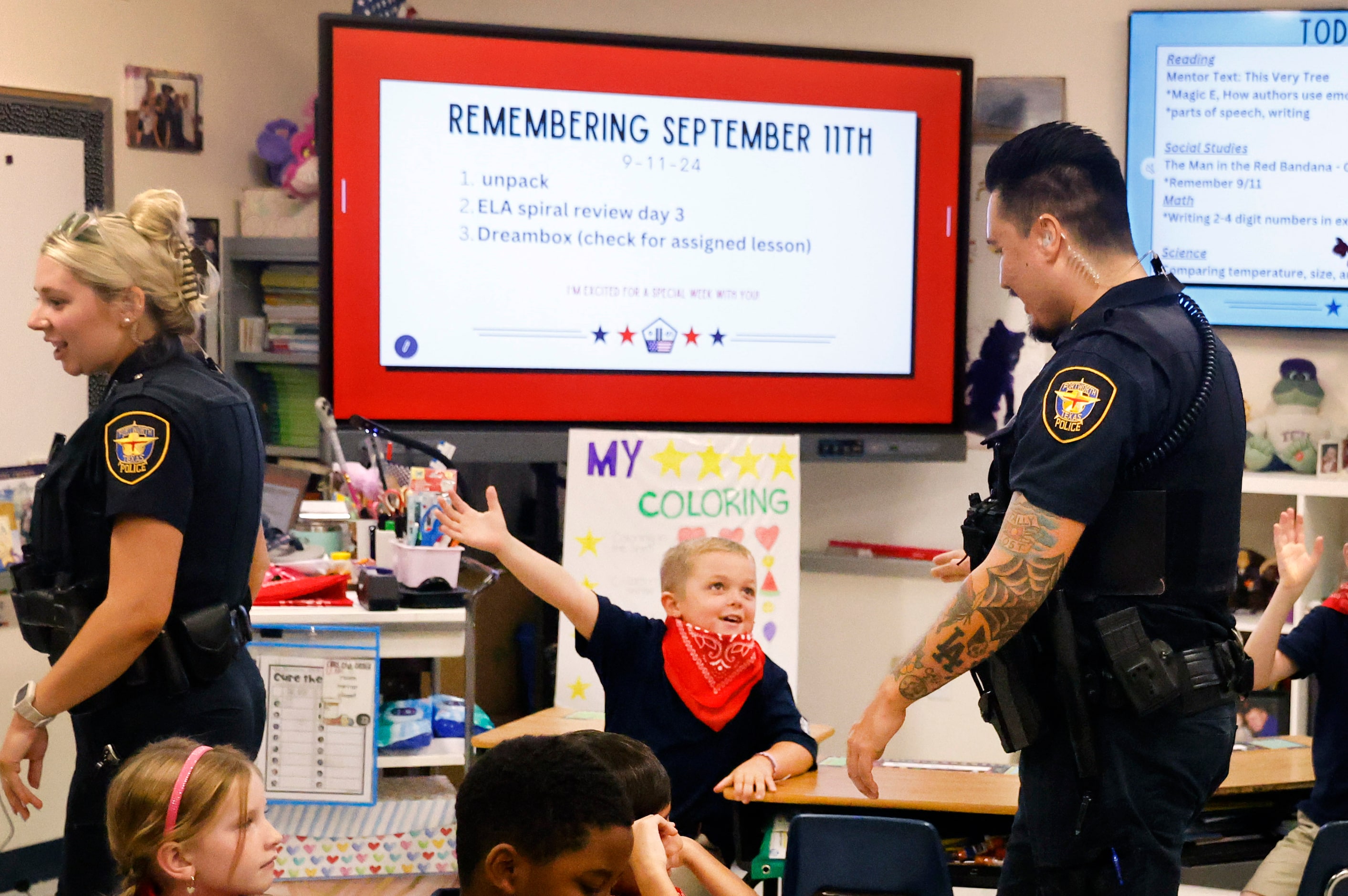 Fort Worth Police officer Daniel Wagner (right) receives a high-five from second grader...