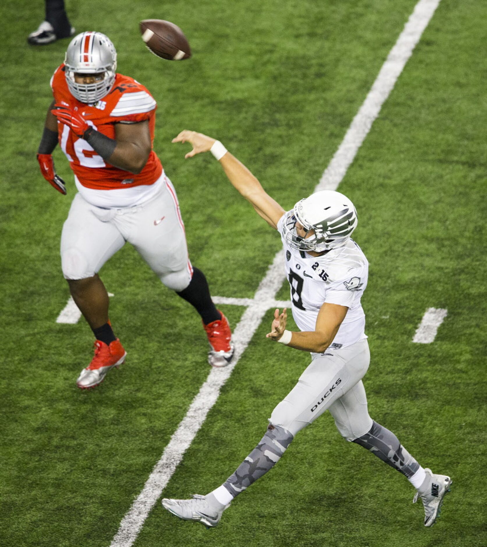 Oregon Ducks quarterback Marcus Mariota (8) launches a pass under pressure from Ohio State...