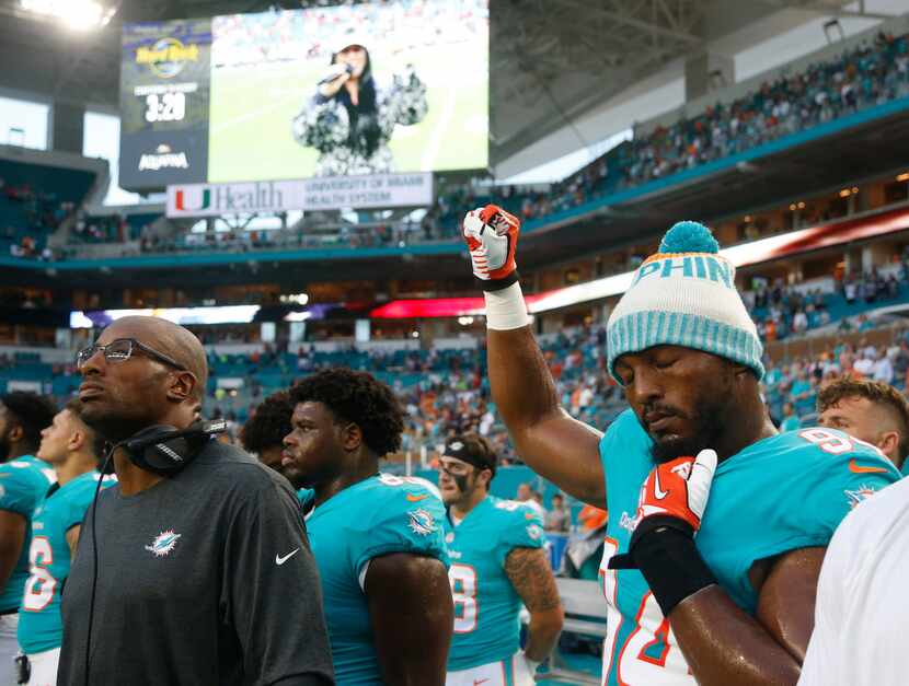 Miami Dolphins defensive end Robert Quinn (94) raises his right fist during the singing of...