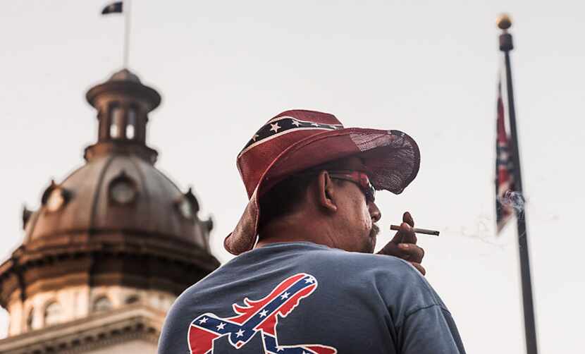 John Blankenship watches the sun rise on Confederate battle flag Friday mornig outside the...