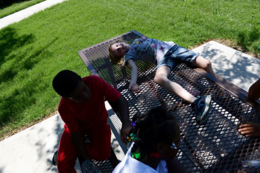Amie Jackson, 7, takes a break in the shade from the heat with friends Jaelon Dennis, 9, and...