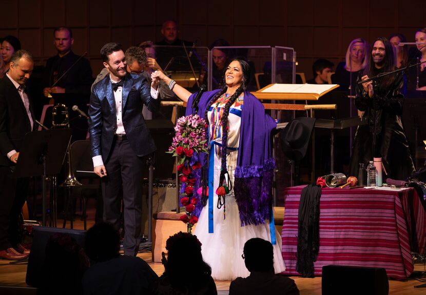 Man in a tuxedo and woman in traditional Mexican dress take a bow onstage in front of...