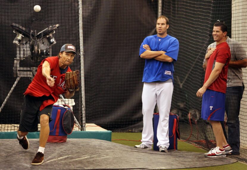 Actor Matthew McConaughey fires a pitch as Texas pitcher Colby Lewis and infielder Michael...