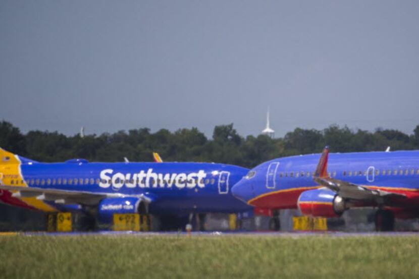 Two Southwest Airlines airplanes cross paths on the runway as others remain parked at...