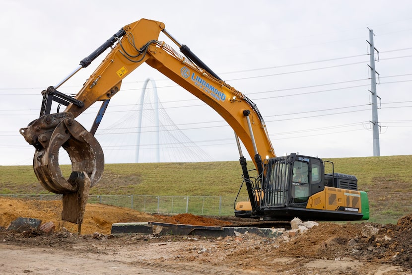 A claw excavator operator removes the concrete retaining walls Nov. 7 from the first three...