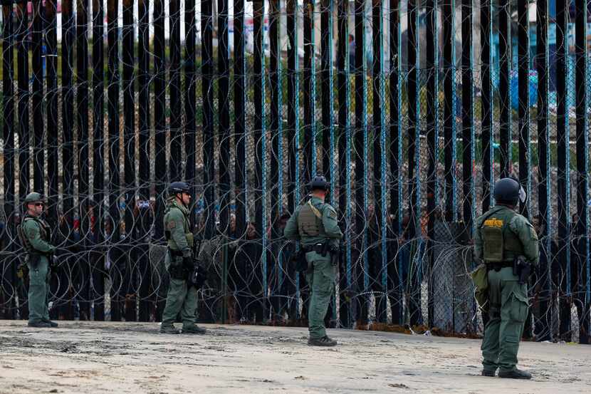 Some south of the border fence watch through the bollard fence as more than 300 faith and...