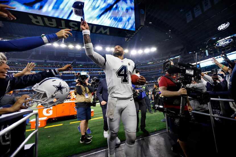 Dallas Cowboys quarterback Dak Prescott (4) tosses his hat to fans as he runs off the field...