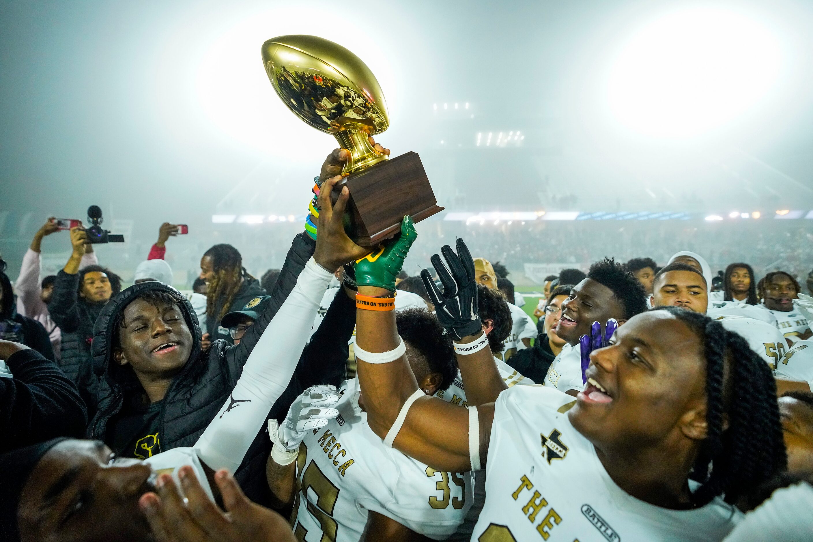 South Oak Cliff players celebrate with the game trophy following a victory over Argyle in a...