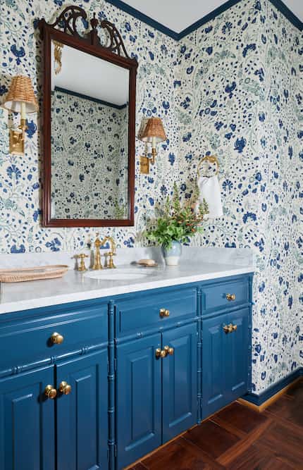 Bathroom interior with blue and white printed wallpaper, white marble countertop, and blue...