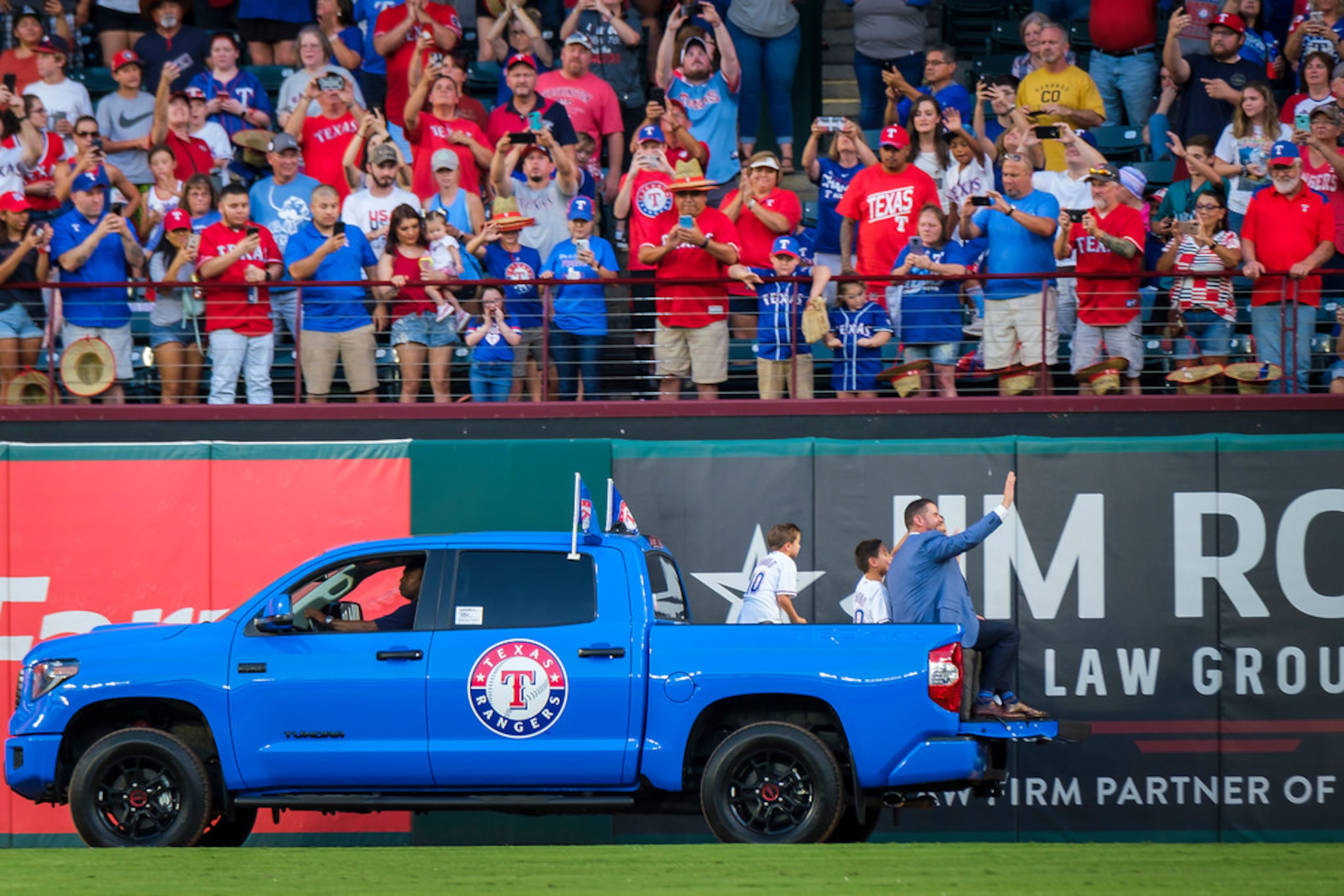 Michael Young waves to the crowd as he rides in a truck with his family after ceremonies to...