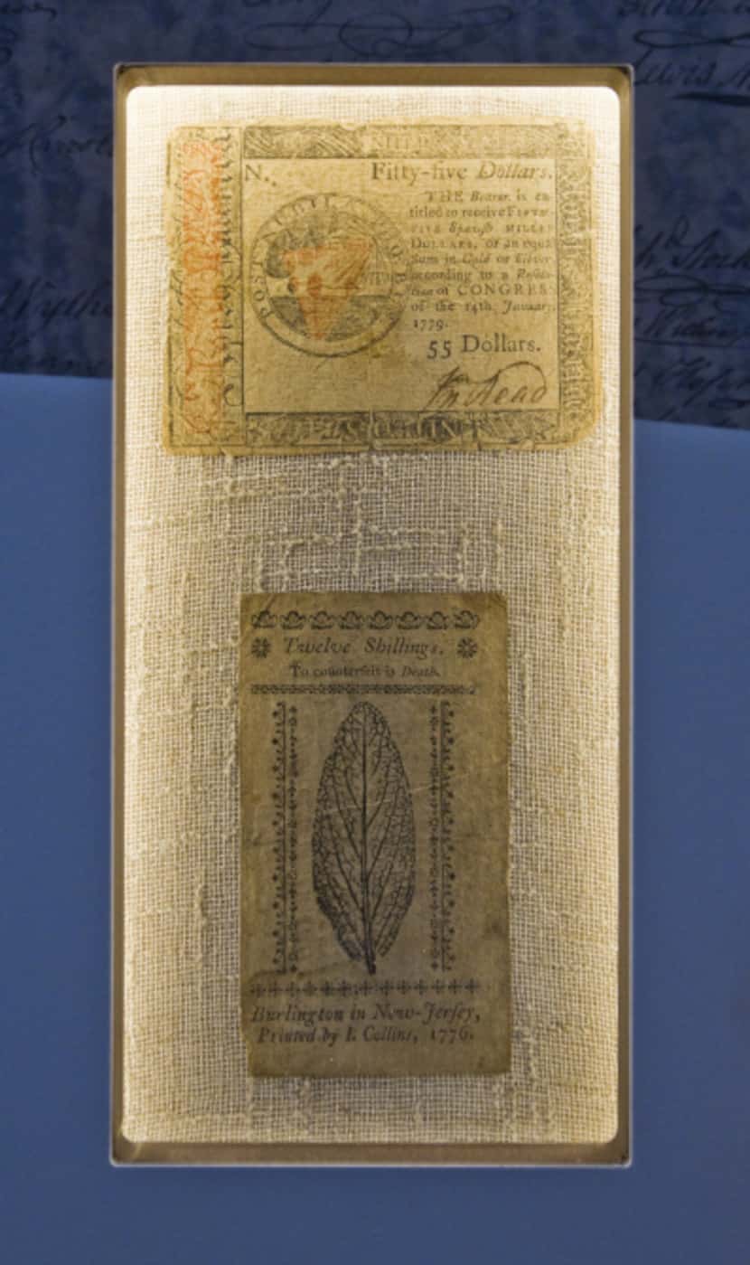 A twelve shilling note, bottom, and a $55 dollar note from 1779, top, on display at the...