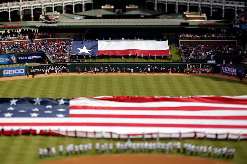 Flags are unfurled before that start of the Texas Rangers opening day game Friday, April 10,...