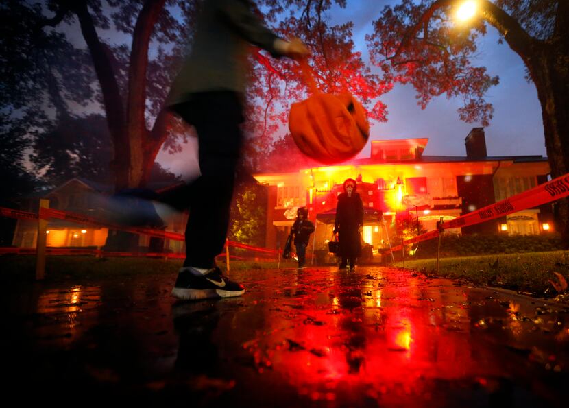Trick-or-treaters skipped over rain puddles in the historic Swiss Avenue neighborhood of...