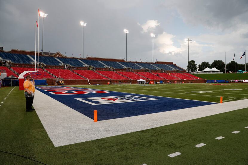 A security guard stands on the field during an inclement weather delay before an NCAA...