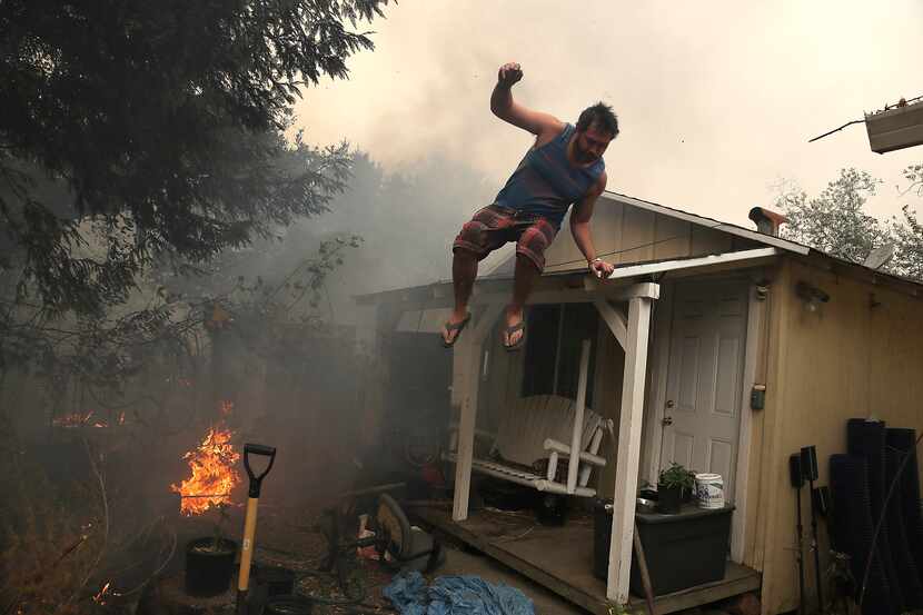 A resident rushes to save his home as an out of control wildfire moves through the area on...