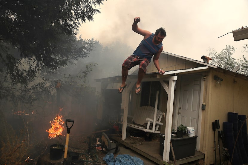 A resident rushes to save his home as an out of control wildfire moves through the area on...