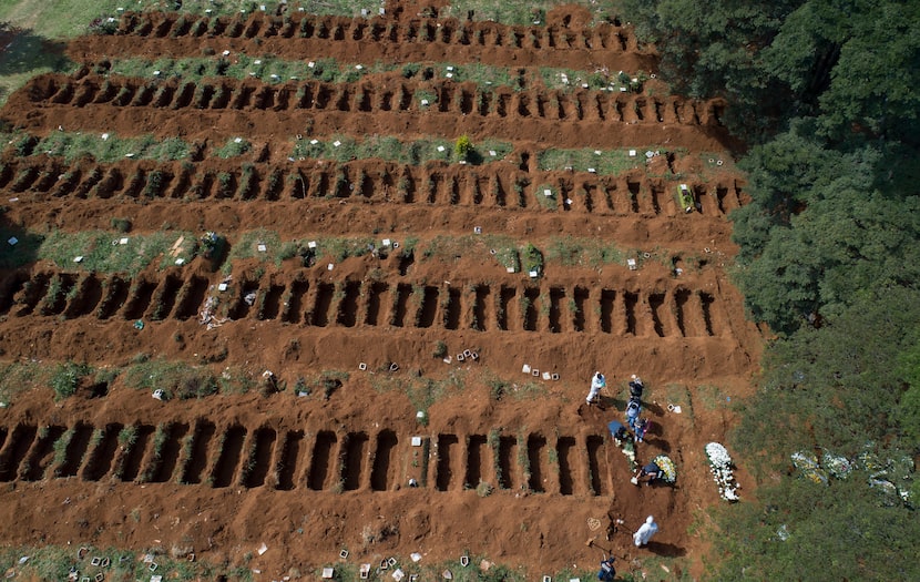 Trabajadores de un cementerio protegidos para un posible contagio junto a fosas recién...