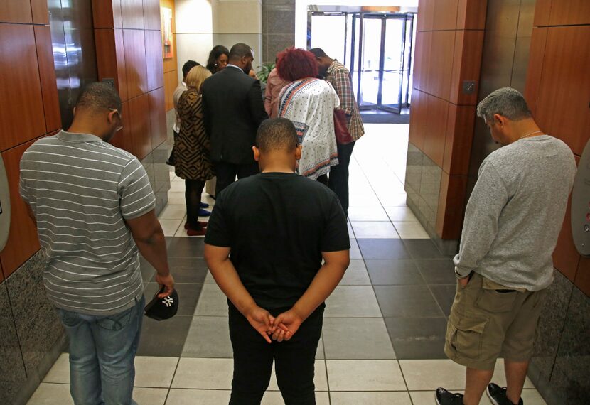 Charmaine (not visible) and Odell Edwards (far right in plaid shirt) stand in a prayer...