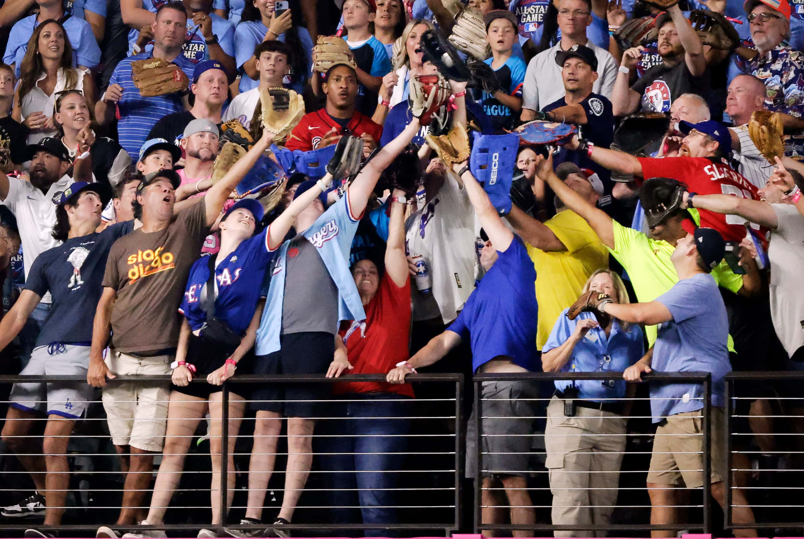 Fans in the left field front row lean to catch a home run by Kansas City Royals Bobby Witt...