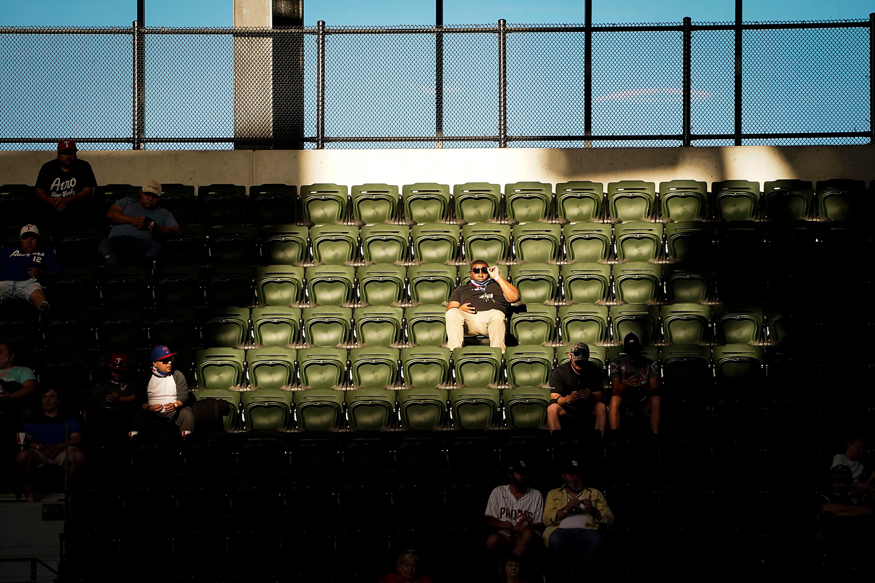 Fans sit in the sun in the upper deck as the Texas Rangers face the San Diego Padres at...