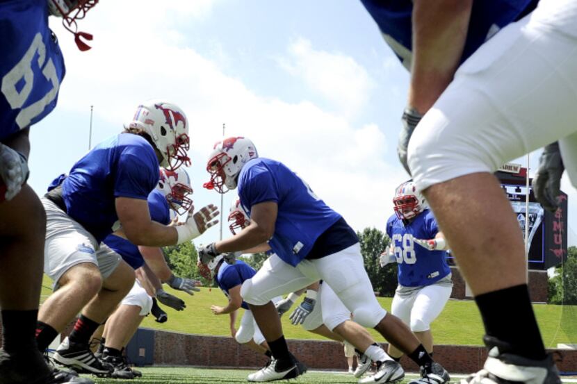 Offensive lineman go through drills before  the SMU spring football scrimmage, Saturday,...