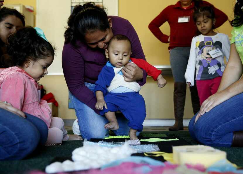 Karen Mena walks her six-month-old son Jose Mena across a cloth with various textures during...