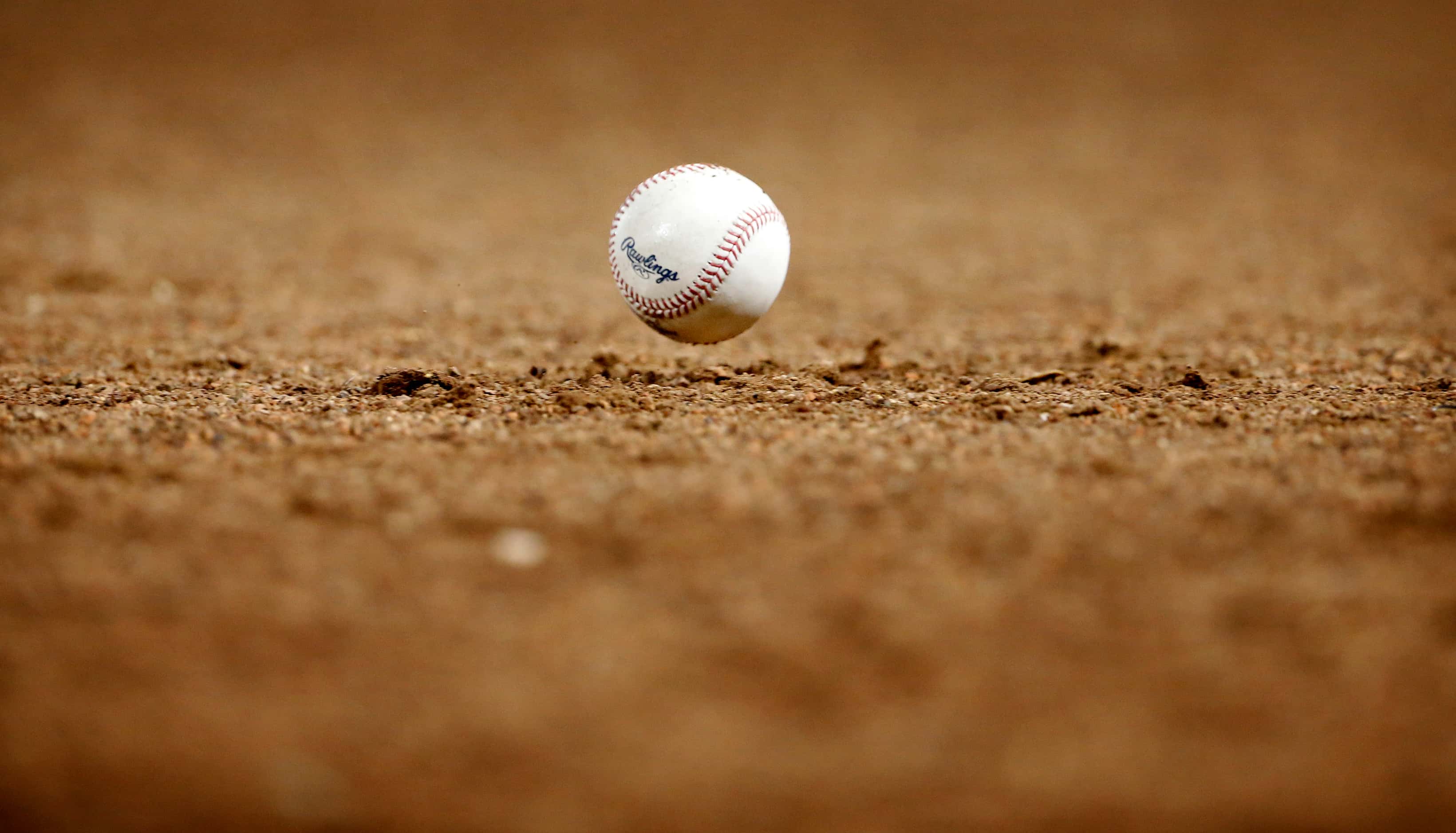 A foul ball bounces in front of the Texas Rangers dugout during a game against the Houston...