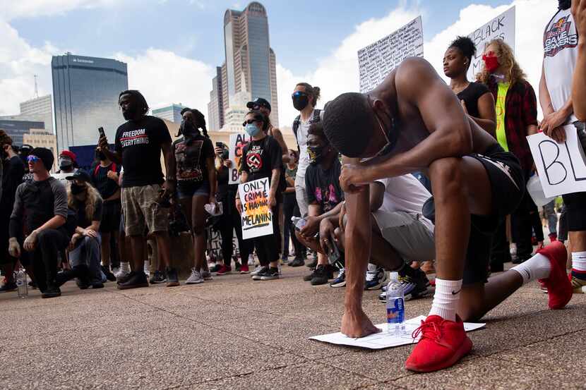 Ryan Hunter of Fort Worth kneels at Dallas City Hall after peacefully marching through...