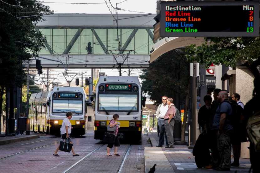 Blue line and Green line trains on the rails as people wait for DART light rail trains at...