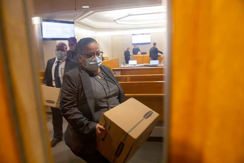 Dallas Police Detectives Christine Ramirez (front) and Jose Ortiz Vives carry out boxes of...