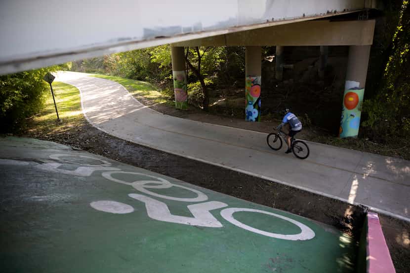 A cyclist rides the Santa Fe Trail under the Brookside Drive bridge on Sunday in Dallas. 