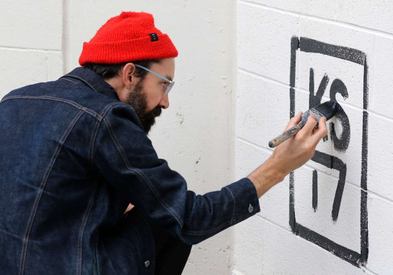 Muralist Kyle Steed signs his name to a mural at Plaza of the Americas. 