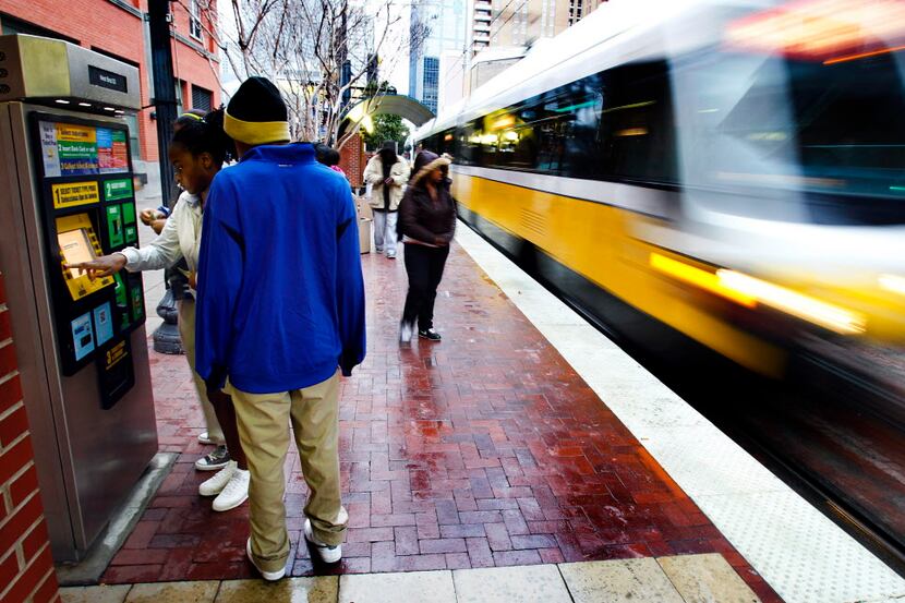  Commuters purchase ride tickets as a DART train enters the West End Station in downtown...