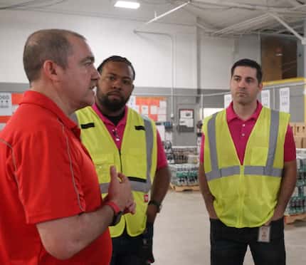 The president of AC-CCSWB meets with two Coca-Cola employees in a warehouse.