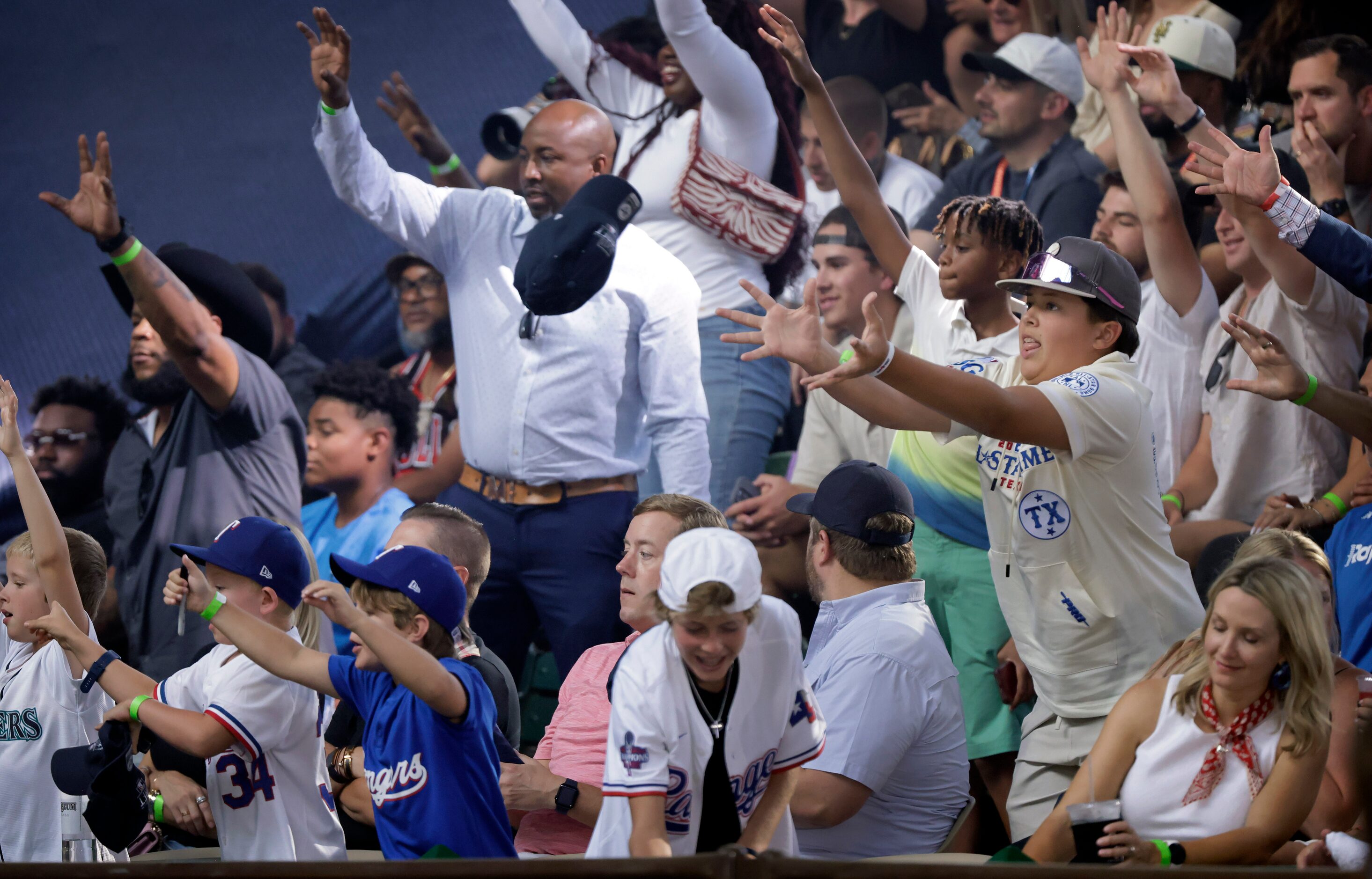 Baseball fans reach for caps thrown into the stands before Day 1 of the MLB Draft at the...