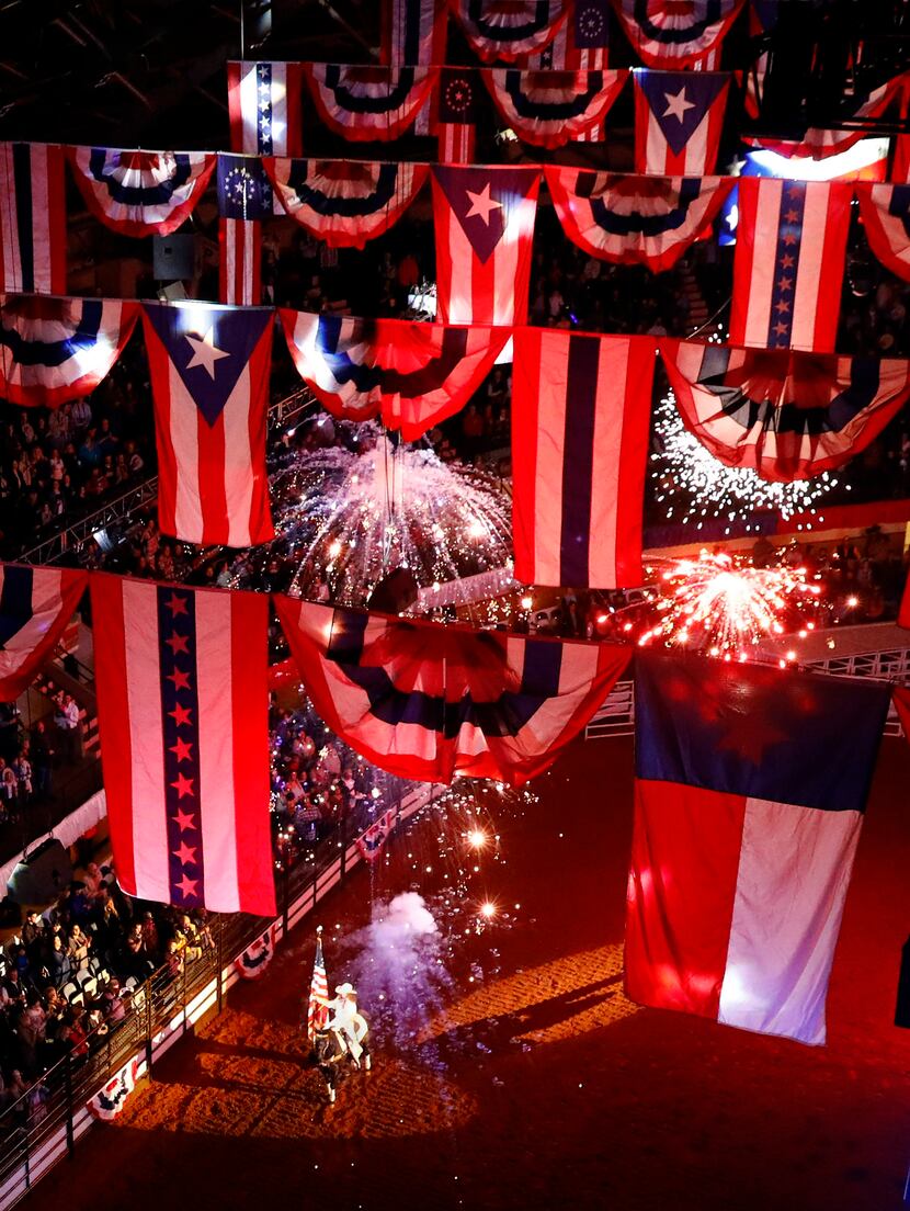 Pyrotechnics explode underneath the patriotic bunting as rider Megan Gay Maier bears the...