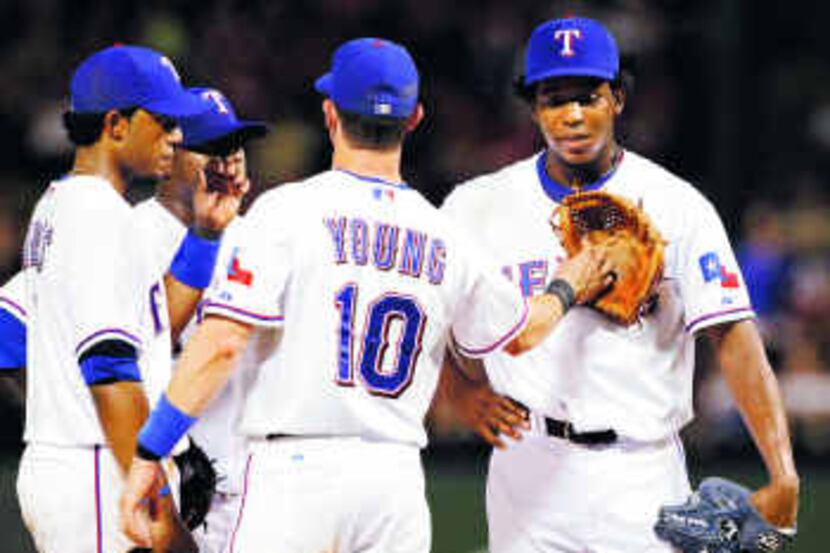  Rangers third baseman Michael Young gives reliever Neftali Feliz a pat on the chest with...