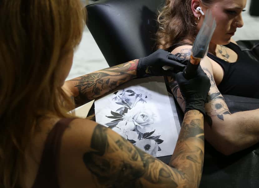 Deanna James refers to her sketch as she tattoos a client.

Credit: Jacob Wells / KERA News