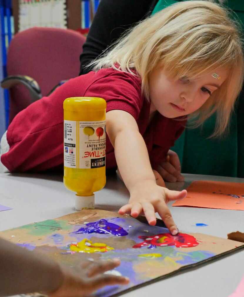 
Ember Davis, 3, picks a color of paint as her class fingerpaints a flower at Little Rascals...